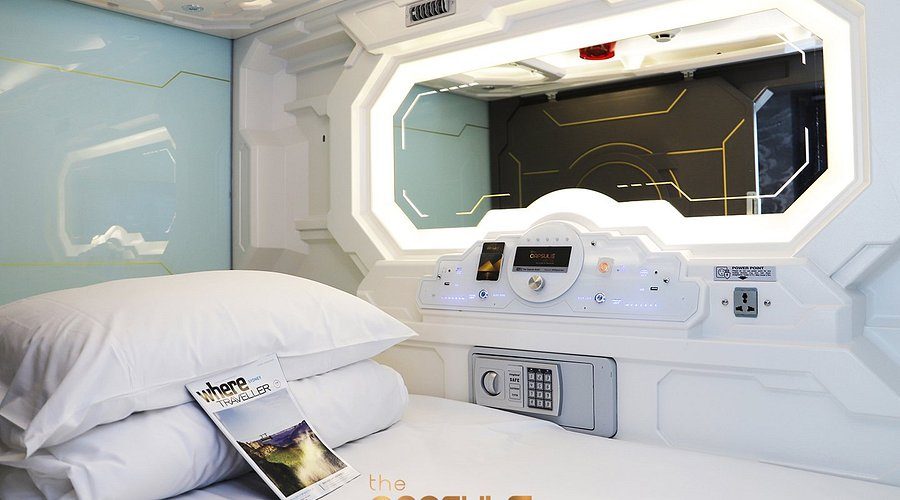The inside of a compact sleeping cabin with a fitted control panel above the bed.